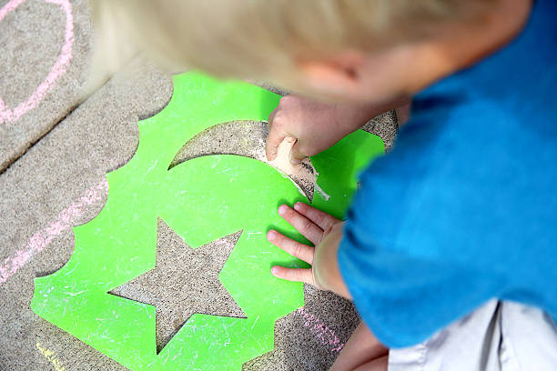 Young Child Drawing Outside with Sidewalk Chalk stock photo