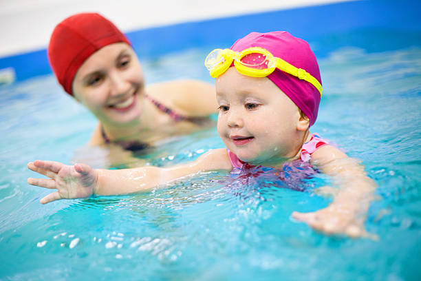 young child learning how to swim with an adult - swimming baby stockfoto's en -beelden