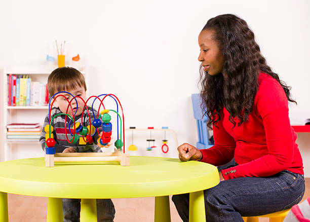 Young child plays with challenging toy in a nursery stock photo