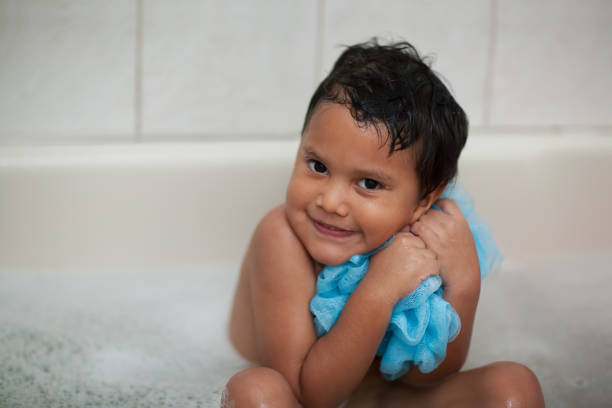 Young child shows that he loves bath time by hugging his wash cloth mesh while soaking his body. stock photo