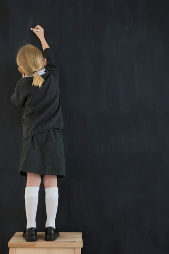 kid writing on chalkboard