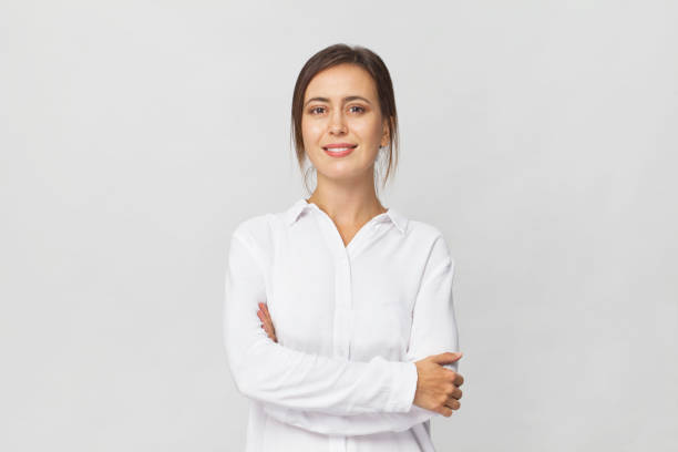 jonge vertrouwen brunette vrouw in wit elegante overhemd lachend portret tegen witte achtergrond - bruin haar stockfoto's en -beelden