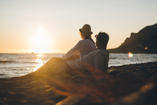 Young modern couple at beach enjoying in sunset by the sea