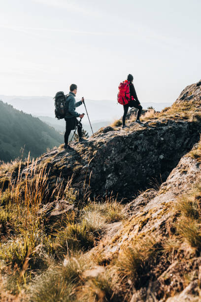 Young couple backpack up a mountain summit stock photo