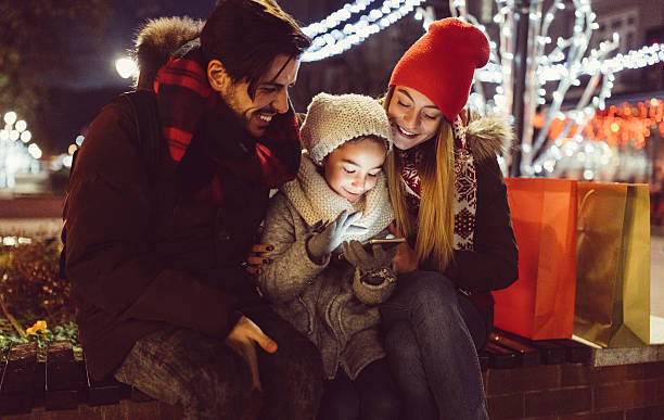 young couple enjoying christmas in the city - smartphone christmas imagens e fotografias de stock