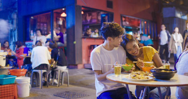 Young couple enjoying street food Young couple enjoying street food. Hong Kong 2019, Shot in 4K night market stock pictures, royalty-free photos & images
