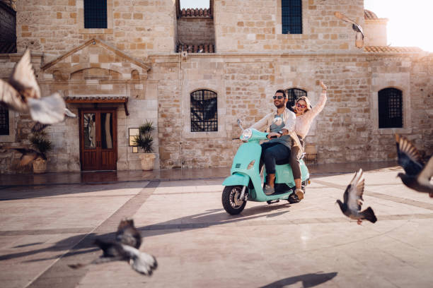 Young couple having fun riding vintage scooter in European town stock photo