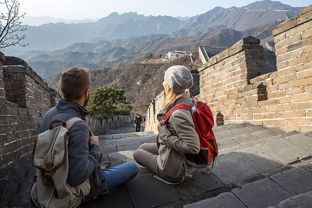 Young couple hiking the Great Wall looking at spectacular landscape-China Young couple on top of the Great Wall of China contemplating the beautiful landscape from high up. View of the wall going on the mountains for kilometres, majestic scenery of a winter day. mutianyu stock pictures, royalty-free photos & images