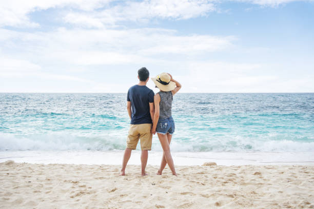 Young couple holding hands and walking on beach stock photo