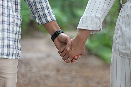 young couple holding hands on natural forest background