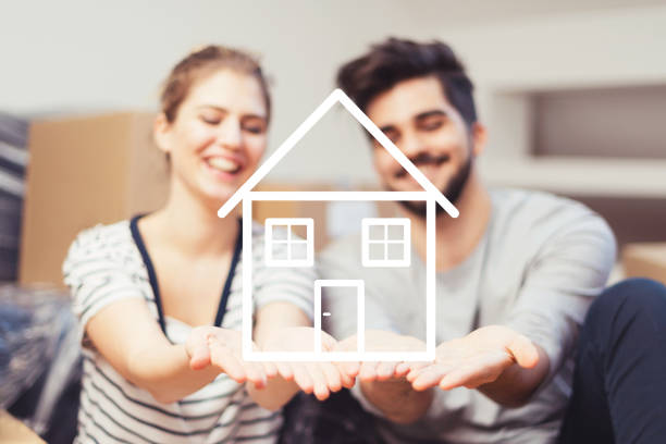 Young couple holding their new, dream home in hands stock photo