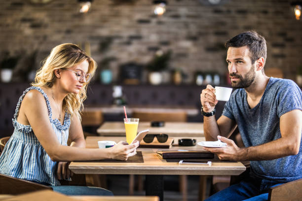 ungt par ignorerar varandra medan du sitter på ett café. - boring date bildbanksfoton och bilder