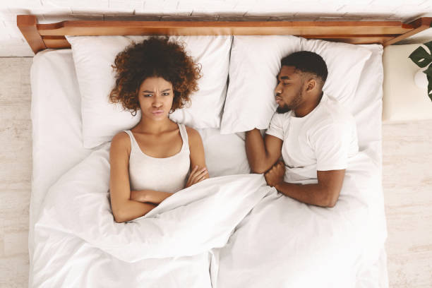 Young couple in bed having problems and crisis Divorce and separation. Millennial african couple in bed having problems, wife angry, husband sleeping, top view man sleeping in bed top view stock pictures, royalty-free photos & images