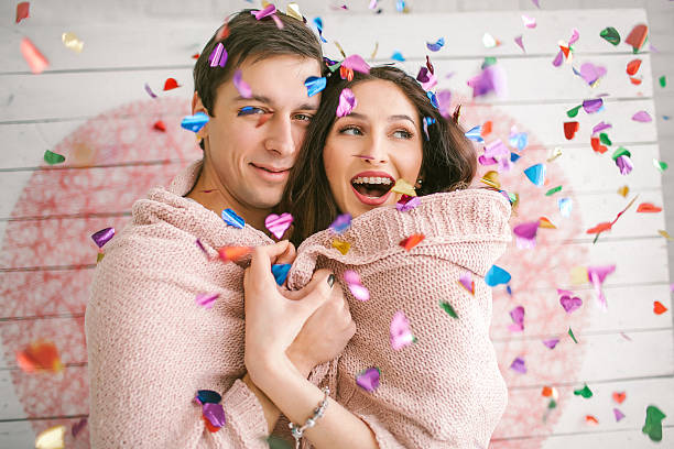 Young couple in love embracing under confetti in decorated studi stock photo