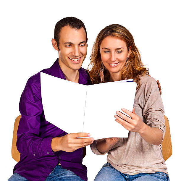 Young couple in love reading together a brochure stock photo
