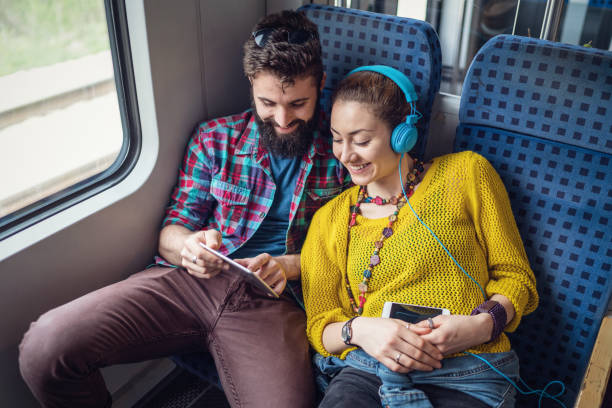 Young couple in the train surfing the net on the tablet stock photo