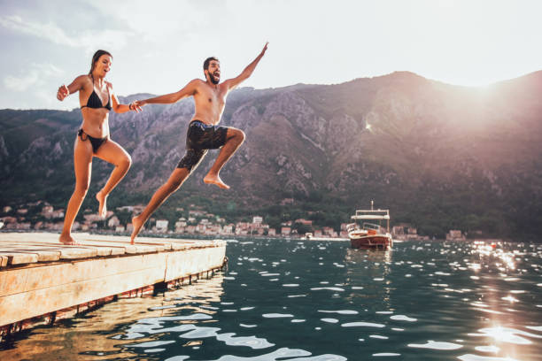 ungt par hoppar från en brygga i vattnet. defocused (på 4)-2 - energetic jumping bokeh bildbanksfoton och bilder