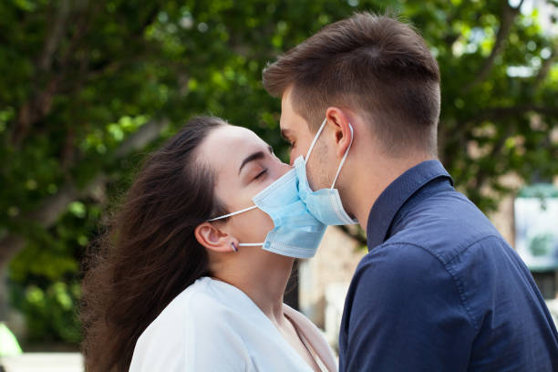 Young couple kissing and wearing protective face masks stock photo