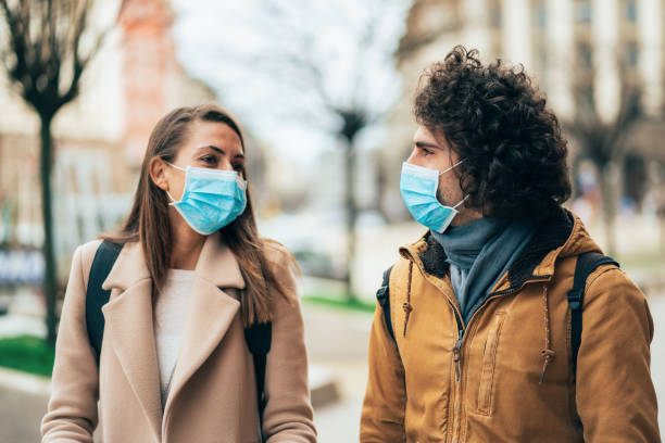 Young couple meet in quarantine Young couple meet in quarantine outside on the city street wearing face protective mask to prevent Coronavirus and anti-smog surgical mask stock pictures, royalty-free photos & images