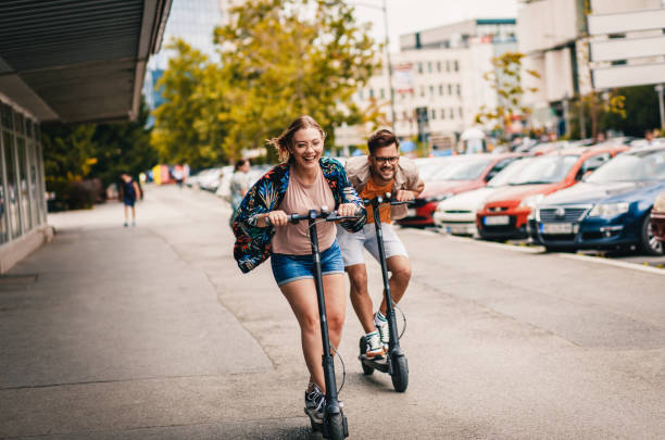 young couple on vacation having fun driving electric scooter through the city. - elektrische step stockfoto's en -beelden