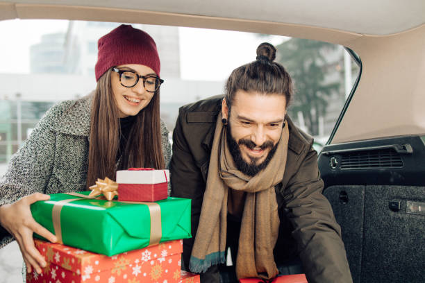 junges paar packt geschenke im auto nach dem weihnachtseinkauf - auto packen für den urlaub winter stock-fotos und bilder
