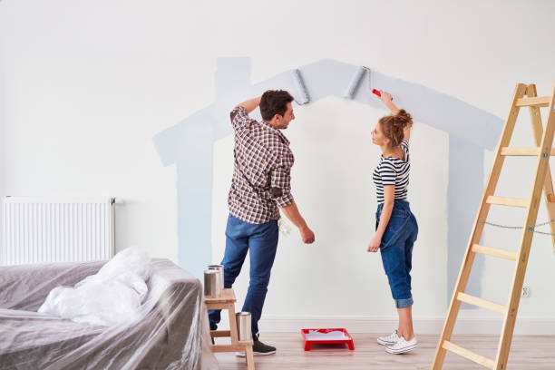 jeunes couples peignant le mur intérieur dans leur nouvel appartement - bricolage photos et images de collection