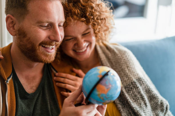 Young couple planning to travel together. Happy young couple looking at globe at home. Searching for the best travel destination. spices of the world stock pictures, royalty-free photos & images
