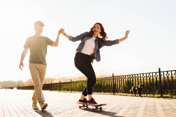 Young Couple practicing skateboarding outdoors stock photo