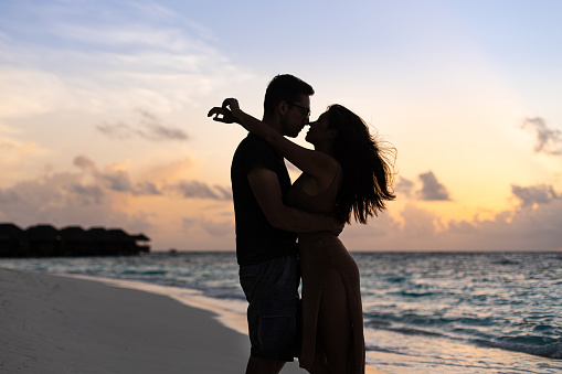 Young couple silhouette hugging on the background of sunset in  Maldives near the Indian ocean