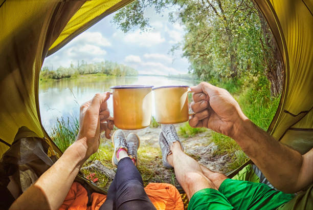 Young couple sitting   in the tent and drinking tea while looking on the Desna river , Ukraine stock photo