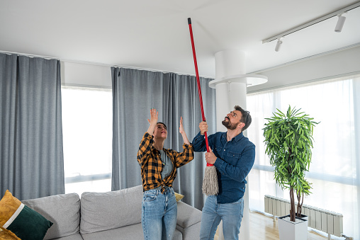 A young couple stares at the ceiling and yells because a neighbor upstairs is having a party with loud music or renovating an apartment and workers are drilling with heavy tools