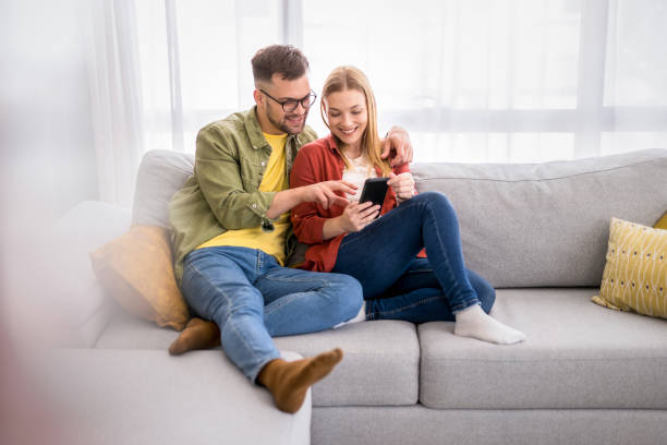 Young couple surfing the net on mobile phone at home. stock photo