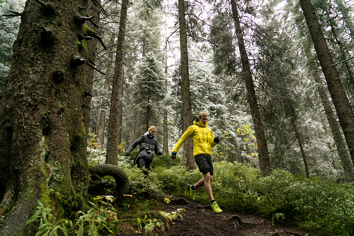 Young couple trail run through a forest with fresh snow