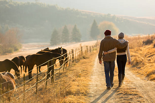 young couple walking in farm road - häst jordbruk bildbanksfoton och bilder