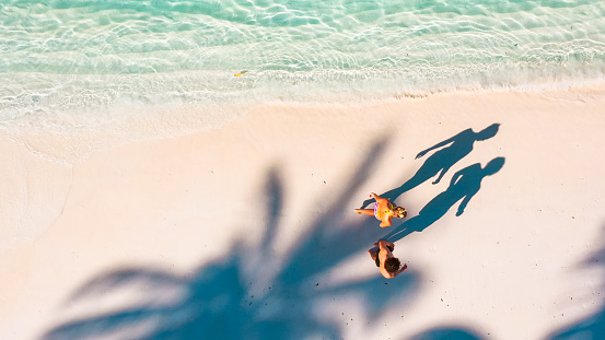 Young couple walking under shade of palm trees in Maldives