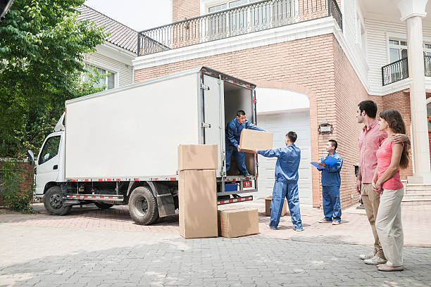 Young couple watching movers move boxes from the moving van stock photo