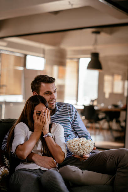 Young couple with popcorn looking horror movie stock photo