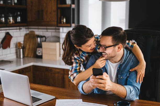 Young couple working out family finances together at home using laptop Young couple working out family finances together at home using laptop mortgages and loans stock pictures, royalty-free photos & images