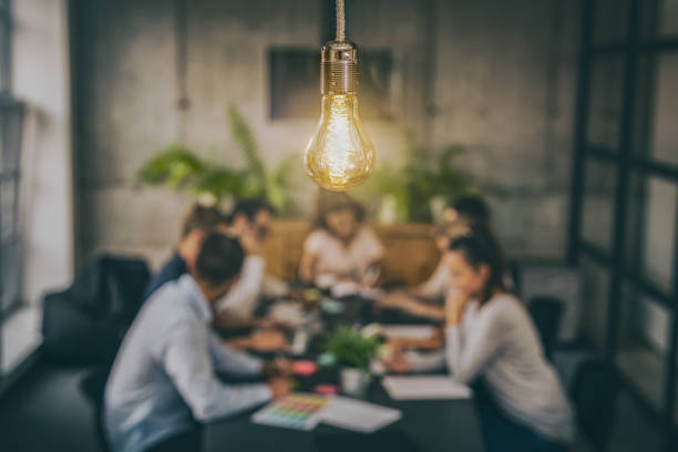 Young creative business people meeting at office. Young business people are discussing together a new startup project. A glowing light bulb as a new idea. business meeting stock pictures, royalty-free photos & images