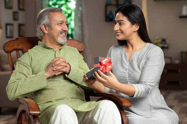young daughter giving a gift box to Father on Father's day and his birthday:- stock photo father and daughter, adult, adult only, birthday gift, father's day,  India, Indian ethnicity, fathers day stock pictures, royalty-free photos & images
