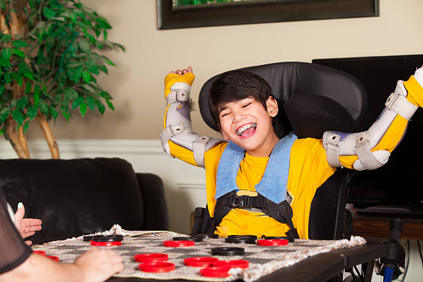 Young disabled boy in wheelchair playing checkers stock photo