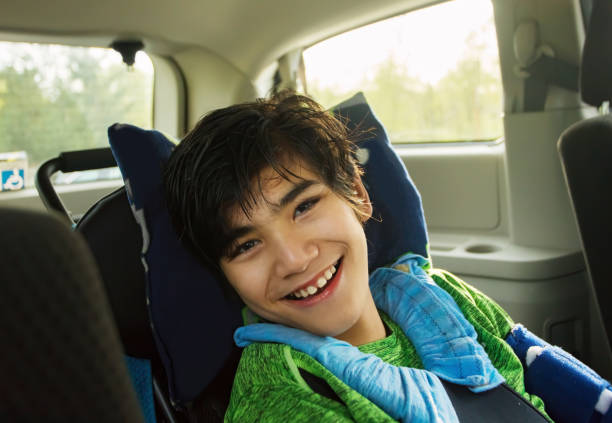 Young disabled boy in wheelchair traveling in handicap vehicle stock photo