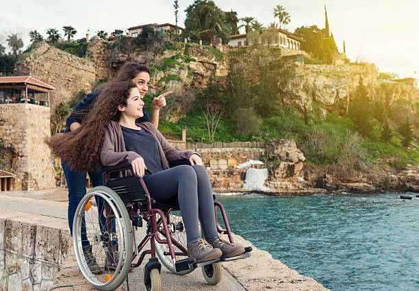 Young disabled woman with friend looking at the sea