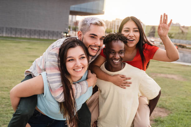 Young diverse people having fun together outdoor at city park - Focus on left girl face stock photo