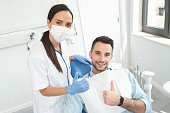 Young doctor dentist and patient showing thumb up. Healthy teeth concept.