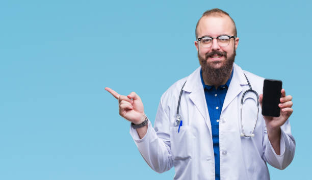 Young doctor man showing smartphone screen over isolated background very happy pointing with hand and finger to the side  fat man looks at the phone stock pictures, royalty-free photos & images