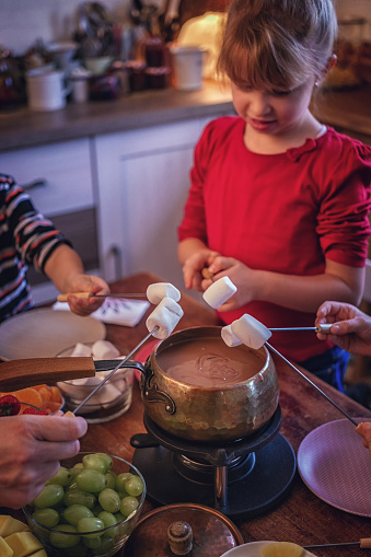 Young Family Having Delicious Chocolate Fondue in a Pot Served with Marshmallows