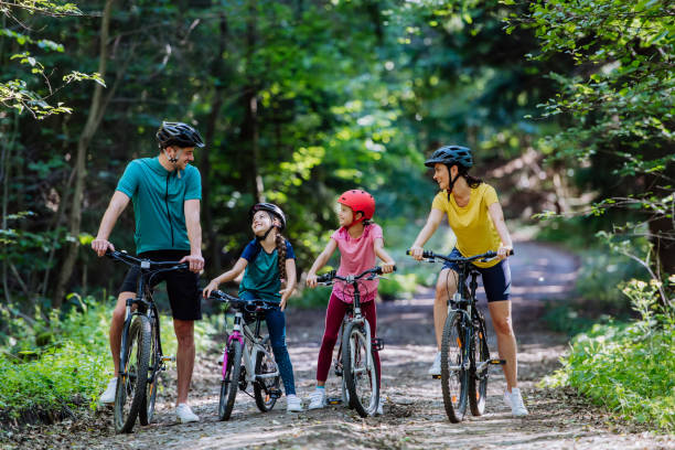 Young family with little children preparing for bike ride, standing with bicycles in nature. stock photo