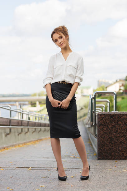 Young fashion business woman in white shirt and pencil skirt with clutch bag stock photo