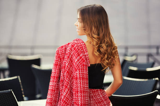 Young fashion woman in red tweed jacket and skirt suit at sidewalk cafe stock photo